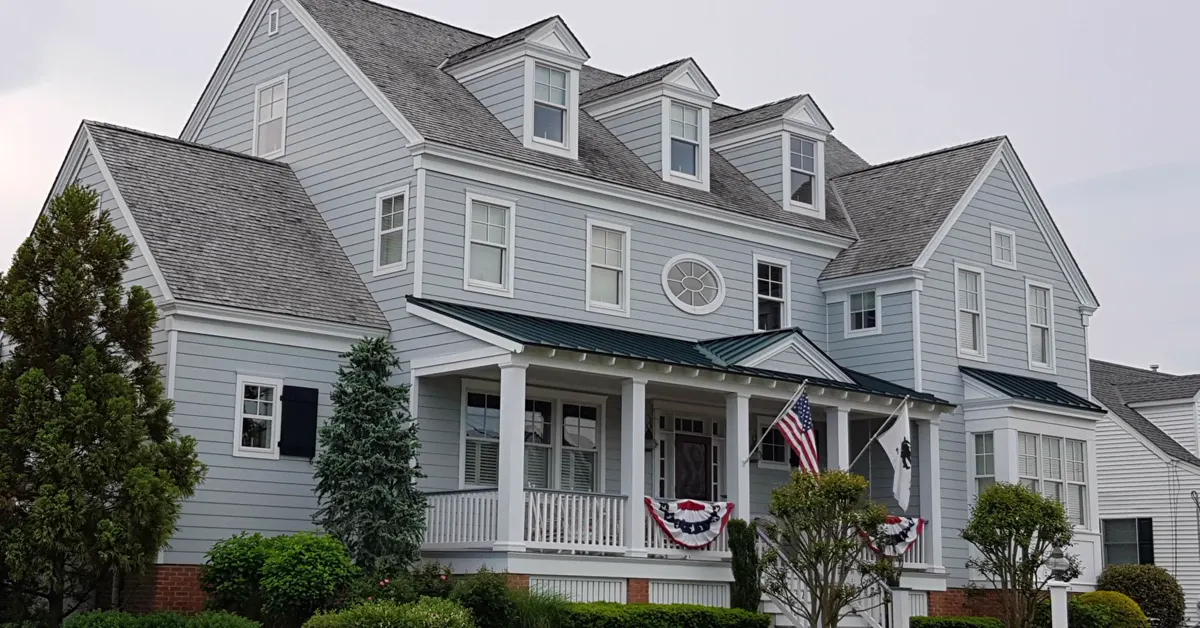 Elegant colonial-style house with manicured lawn and American flags.